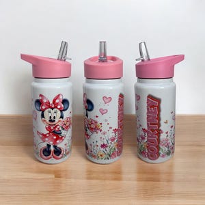 May include: Three white water bottles with pink lids and straws. One bottle features Minnie Mouse holding flowers, another has a floral design with hearts, and the third displays the name "COURTNEY" in red.