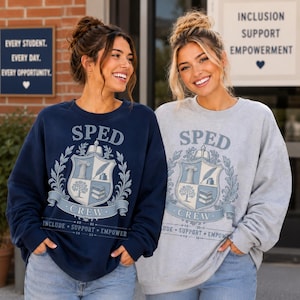 May include: A navy blue sweatshirt and a light gray sweatshirt, each featuring a central crest graphic with the text SPED CREW and the words INCLUDE SUPPORT EMPOWER. The crest design includes a book, a pillar, a feather quill, and a tree.