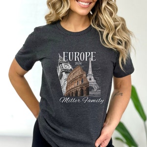 May include: A dark gray t-shirt with a white graphic design featuring iconic European landmarks, including Big Ben, the Colosseum, and the Eiffel Tower. The text "Europe 2024 Miller Family" is printed below the landmarks.