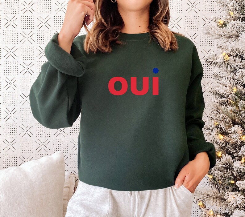 May include: A dark green sweatshirt with a red "oui" graphic and a small blue dot.