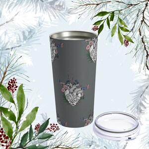 May include: A gray stainless steel tumbler with a floral and anatomical heart design. The tumbler has a lid and is perfect for hot or cold beverages.