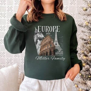 May include: A dark green sweatshirt with a white graphic design featuring iconic European landmarks, the text "Europe 2024", and the words "Miller Family".