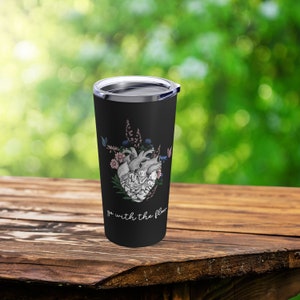 May include: Black stainless steel tumbler with a white anatomical heart graphic surrounded by flowers and butterflies. The text "go with the flow" is printed below the heart.