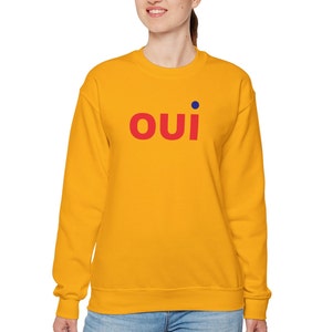 May include: A yellow sweatshirt with the word "OUI" in red letters and a blue dot above the "I".