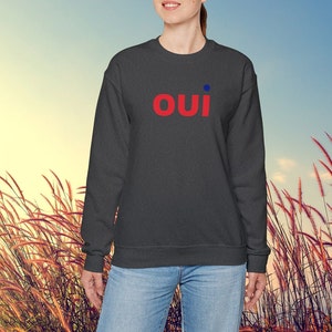 May include: A dark gray sweatshirt with the word "OUI" in red letters with a blue dot above the "I".