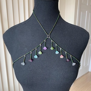 May include: A beaded body chain with a criss-cross design and flower-shaped charms in various colors, including clear, pink, purple, green, and blue.