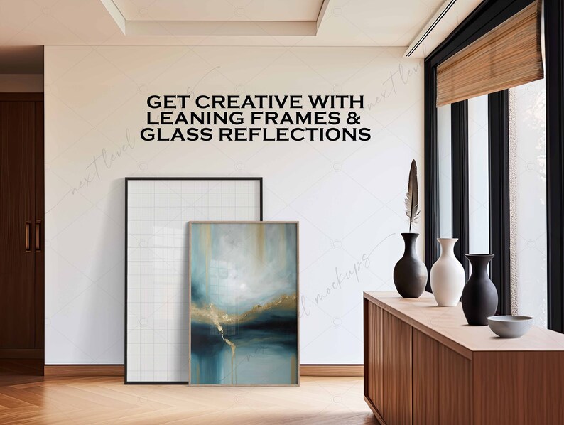 Może przedstawiać: Biała ściana z tekstem "GET CREATIVE WITH LEANING FRAMES & GLASS REFLECTIONS" w kolorze czarnym. Biała rama z siatką opiera się o ścianę obok abstrakcyjnego obrazu w kolorze niebieskim i złotym w drewnianej ramie. Przed ścianą stoi drewniana komoda z trzema wazami i miską.