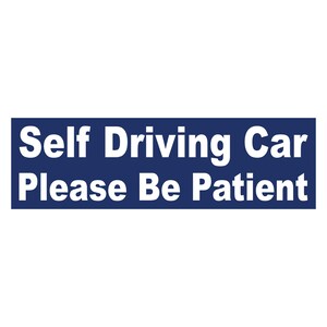 May include: A blue sign with white text that reads "Self Driving Car Please Be Patient".