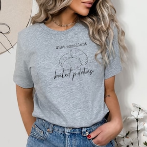 Może przedstawiać: Szary T-shirt z napisem "What excellent boiled potatoes." i rysunkiem trzech ziemniaków.