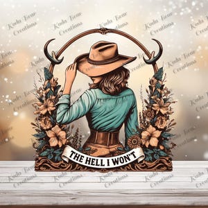May include: A graphic illustration featuring a person wearing a tan cowboy hat and a teal long-sleeved shirt, framed by brown antlers and floral elements. A white banner at the bottom displays the black text THE HELL I WON'T in capital letters.