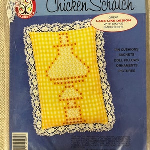 May include: A craft kit for making a chicken scratch cushion. The kit includes yellow and red gingham fabric, white lace trim, embroidery floss, and instructions. The kit is labelled "Chicken Scratch" and "Great Lace-Like Design with Simple Embroidery".