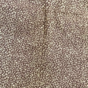 May include: A close-up of a fabric with a brown background and a white, speckled pattern.