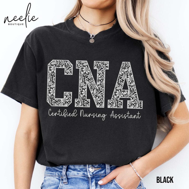 May include: Black t-shirt with a white floral design spelling out "CNA" and the text "Certified Nursing Assistant".