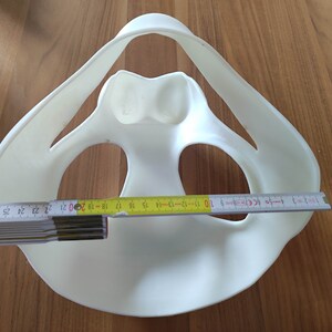 May include: White plastic model of a human pelvis with a ruler measuring 20 inches across the widest part.