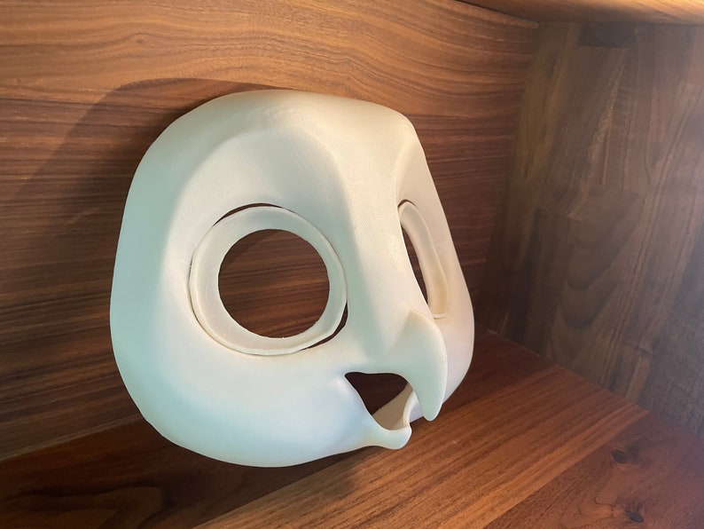 May include: White unpainted owl mask with large eye holes and a beak. The mask is made of a smooth, hard material and is ready for painting.