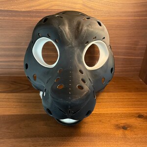 May include: A black and white furry animal mask with holes for the eyes and nose. The mask is made of a smooth, hard material and has a realistic look.
