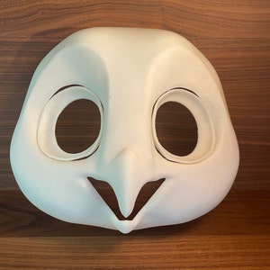 May include: White unfinished owl mask with eye and mouth openings. The mask is made of a smooth, hard material.