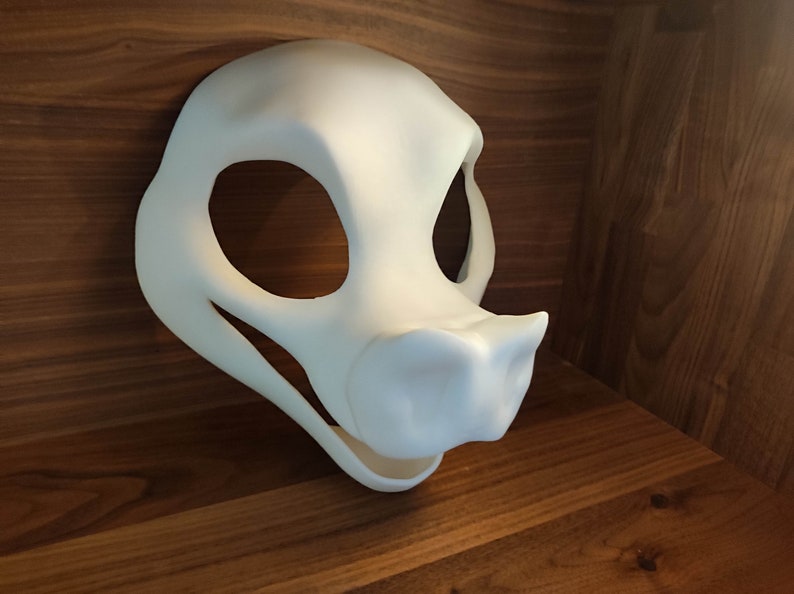 May include: A white, unpainted, resin fursuit head base with large eye holes and a snout. The head base is designed for a canine or wolf character.