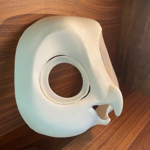 May include: White 3D printed owl mask with a large eye opening and a beak. The mask is made of a smooth, white plastic.