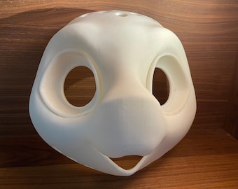 May include: White unfinished resin blank for a furry animal mask. The mask has two large eye holes and a small nose hole.