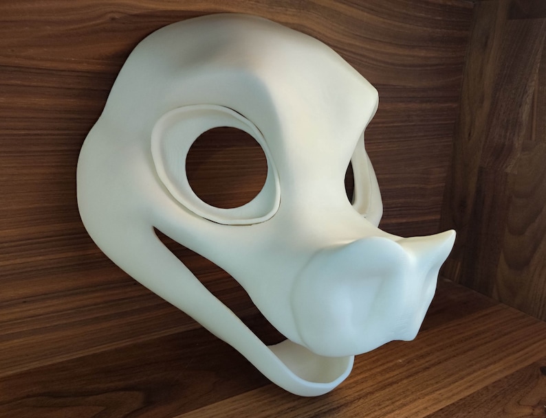 May include: White unfinished resin blank fursuit head base with large eyes and a snout. The head is designed for a canine or similar animal.