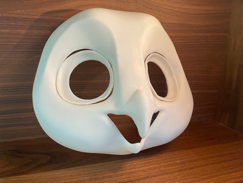 May include: White unfinished owl mask with large eye holes and a beak. The mask is made of a smooth, hard material.
