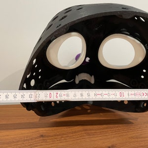 May include: Black plastic mask with white eye holes and a white mouth. The mask is 50.8 cm wide.