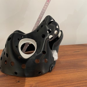 May include: A black 3D printed mask with a white interior and multiple holes. The mask is shaped like an animal head and has a long snout.