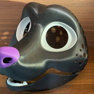 May include: A black and white furry mask with a purple nose and a white eye area. The mask has a textured surface and is designed for cosplay or furry fandom.