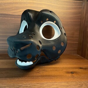 May include: A black and white 3D printed furry mask with holes for eyes and a mouth. The mask is designed to look like an animal head.
