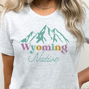 May include: A heather grey t-shirt with a graphic of mountains and the text "Wyoming Native" in colorful letters.