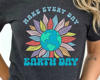 Puede incluir: Una camiseta gris oscuro con un gráfico de flor colorido y el texto "Make Every Day Earth Day" en una fuente retro.