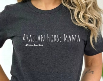 May include: Dark gray t-shirt with the text "ARABIAN HORSE MAMA" in white, with the hashtag "#TeamArabian" underneath. The shirt is a short-sleeved crew neck style.