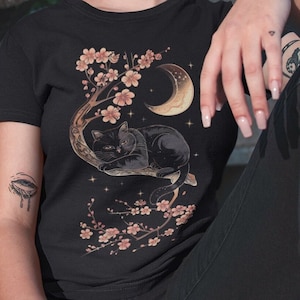 May include: Black t-shirt with a graphic of a black cat sleeping on a branch of a cherry blossom tree with a crescent moon in the background.