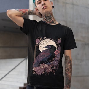 May include: Black t-shirt featuring a graphic print of a raven perched on a branch with flowers and a moon in the background.