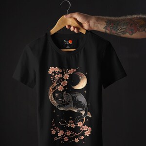 May include: Black t-shirt with a graphic of a black cat sleeping in a cherry blossom tree under a crescent moon. The text "Empress of the Night" is on the shirt.