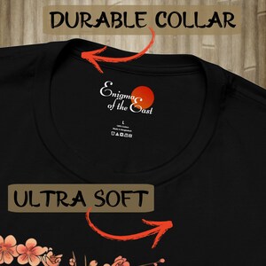 May include: Black t-shirt with a white and red logo that says "Enigma of the East". The shirt has a durable collar and is ultra soft.