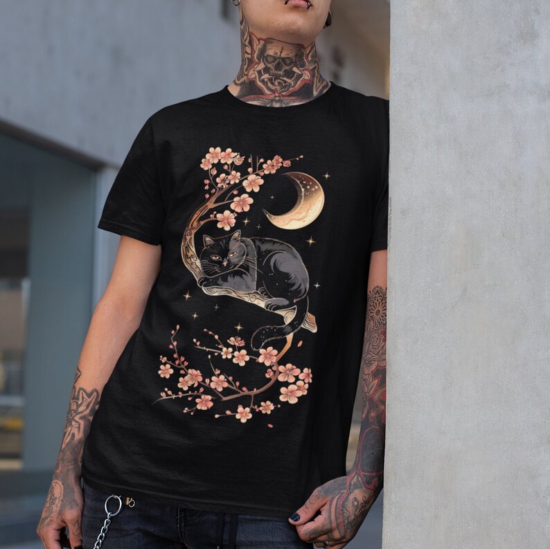 May include: Black t-shirt with a graphic of a black cat sleeping in a cherry blossom tree with a crescent moon in the background.