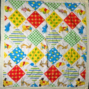 May include: A quilted blanket featuring a diamond-patterned patchwork design with alternating squares of white fabric printed with Winnie the Pooh characters, red floral fabric, green gingham, blue balloons, and multi-colored stripes.