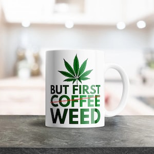 May include: White ceramic mug featuring a green cannabis leaf design and the text "But First Weed" with the word "Coffee" crossed out.