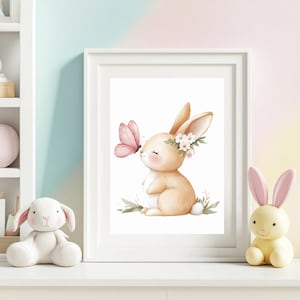 Pode incluir: Uma impress&atilde;o em aquarela emoldurada com um coelhinho charmoso com uma coroa de flores, tocando suavemente uma borboleta rosa. A obra de arte tem uma paleta de cores pastel, perfeita para um quarto infantil. O coelho est&aacute; sentado em folhas verdes.