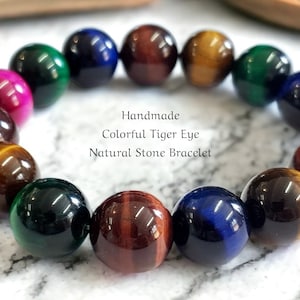May include: Handmade bracelet crafted from colourful tiger eye stones. The bracelet features a range of colours, including brown, gold, green, blue, and red. The bracelet is made with natural stones and is a beautiful and unique piece of jewellery.