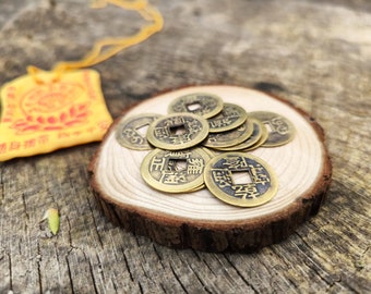 May include: A pile of Chinese lucky coins with a square hole in the centre, each coin has Chinese characters on it, the coins are on a wooden surface.
