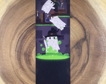 May include: A bookmark featuring a cartoon illustration of three ghosts wearing witch hats. The ghosts are in a dark room with a cauldron of green bubbling liquid. The top ghost is flying, the middle ghost is reaching into the cauldron, and the bottom ghost is stirring the liquid with a wand.