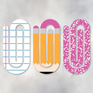 May include: Three stylised paperclip designs. One is white with blue lines, resembling notebook paper. The second is a yellow pencil with a pink eraser. The third is pink with a white speckled pattern, like a composition notebook.