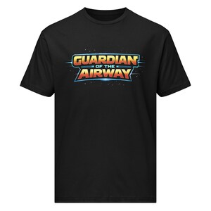 Pode incluir: T-shirt preta com o texto "GUARDIAN OF THE AIRWAY" em um design estilizado e colorido. O texto é em laranja, amarelo e azul, com uma fonte futurista. A camiseta é feita de um material macio.