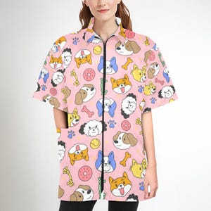Peut inclure: Chemise rose à manches courtes avec fermeture éclair et motif de chiens de dessin animé, d'os et de beignets.
