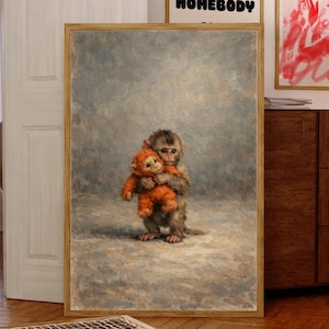 May include: A framed artwork featuring a monkey hugging an orange stuffed animal. The artwork has a neutral color palette with a light brown wooden frame. The background is a soft, textured gray.