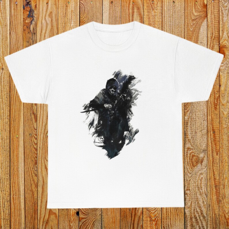 Op de afbeelding: Wit T-shirt met een zwart-witte grafische print van een gekapte figuur die een wapen vasthoudt. De figuur is omringd door een zwart-wit abstract ontwerp.