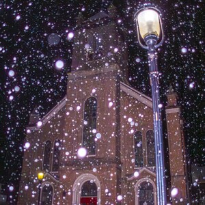 Könnte beinhalten: Eine Backsteinkirche mit einer roten Tür steht unter einem verschneiten Nachthimmel. Eine Straßenlaterne mit einem leuchtenden Licht beleuchtet die Szene.